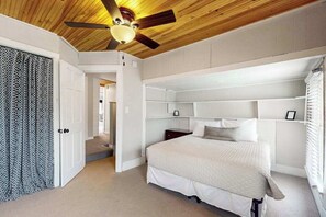 Ein Schlafzimmer mit einem Bett, einem Deckenventilator und eingebauten Regalen.