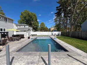Ein rechteckiger Pool mit einem durch ein Netz abgetrennten Bereich, umgeben von einer Betonplattform.