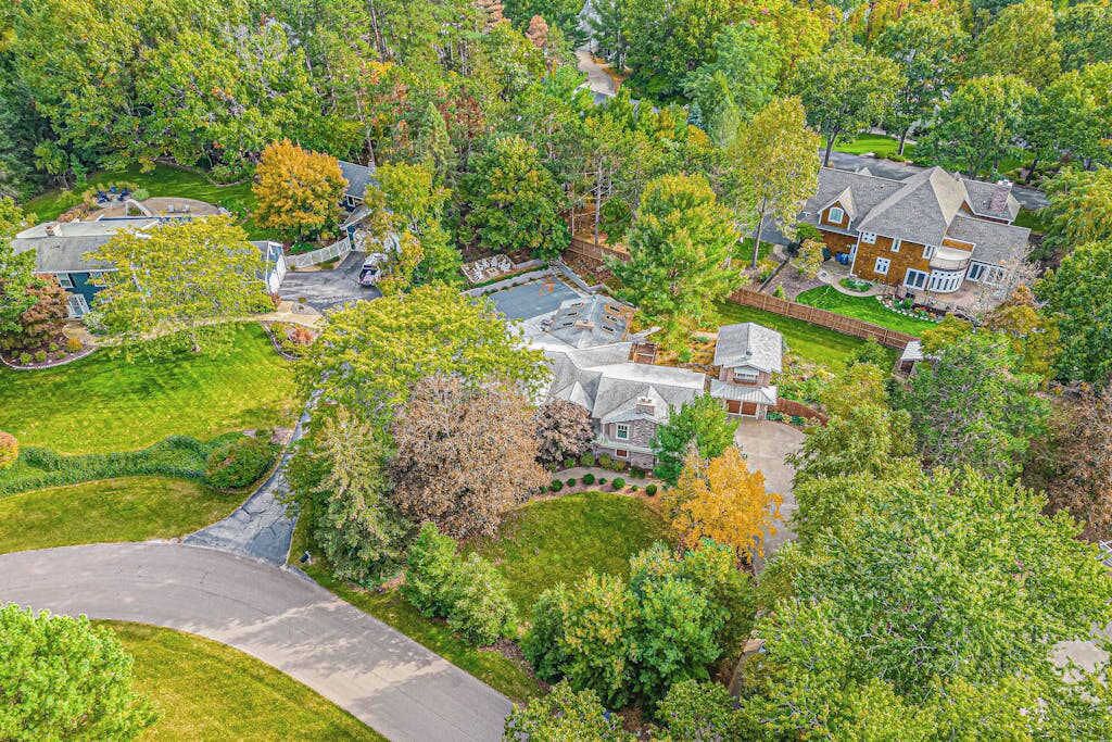 A residential area with a large house featuring a spacious front yard, a driveway, and a well-maintained lawn.