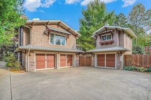 Une maison à deux étages avec un garage, une façade en pierre et un toit en métal.