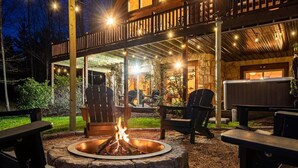 Eine Holzhütte mit Feuerstelle, Sitzgelegenheit im Freien und Whirlpool.