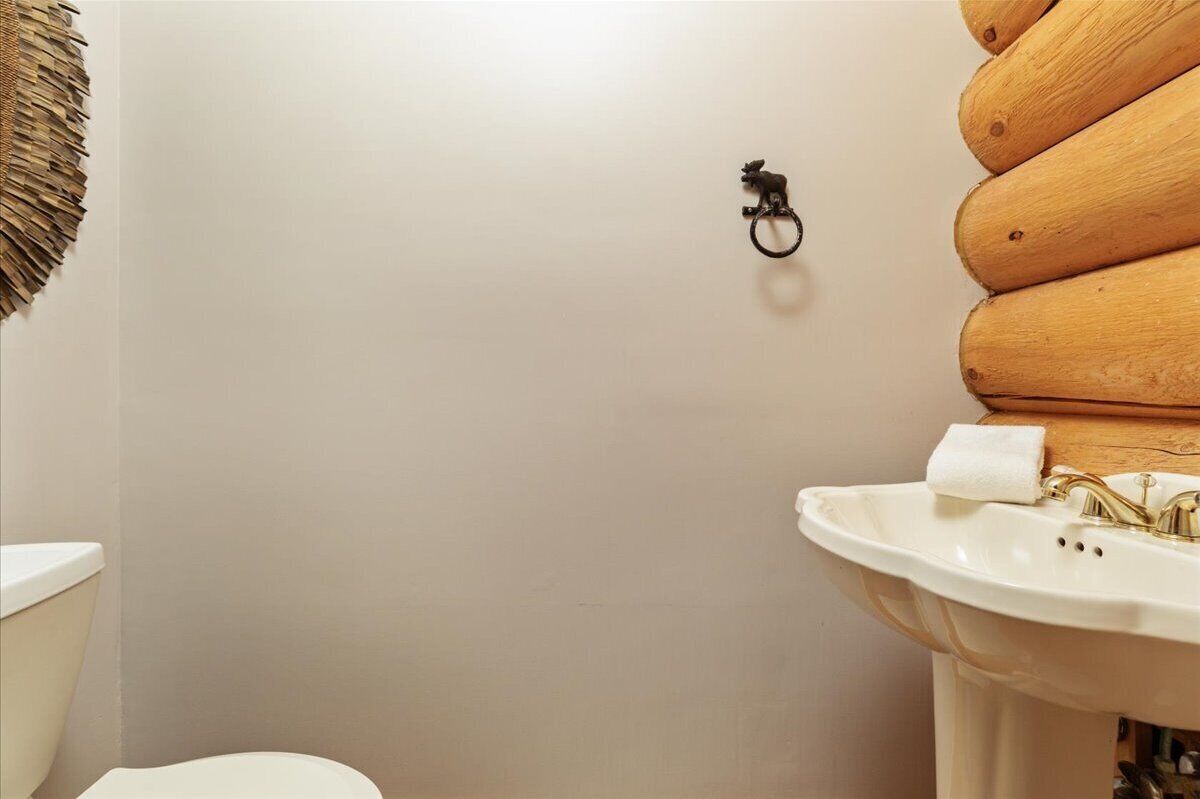 A bathroom with a toilet, sink, and wooden wall paneling.