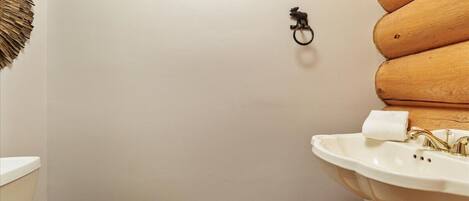 A bathroom with a toilet, sink, and wooden wall paneling.