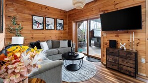 Ein Holzinnenraum mit einer Couch, einem Fernseher und einer Treppe, die nach draußen führt.