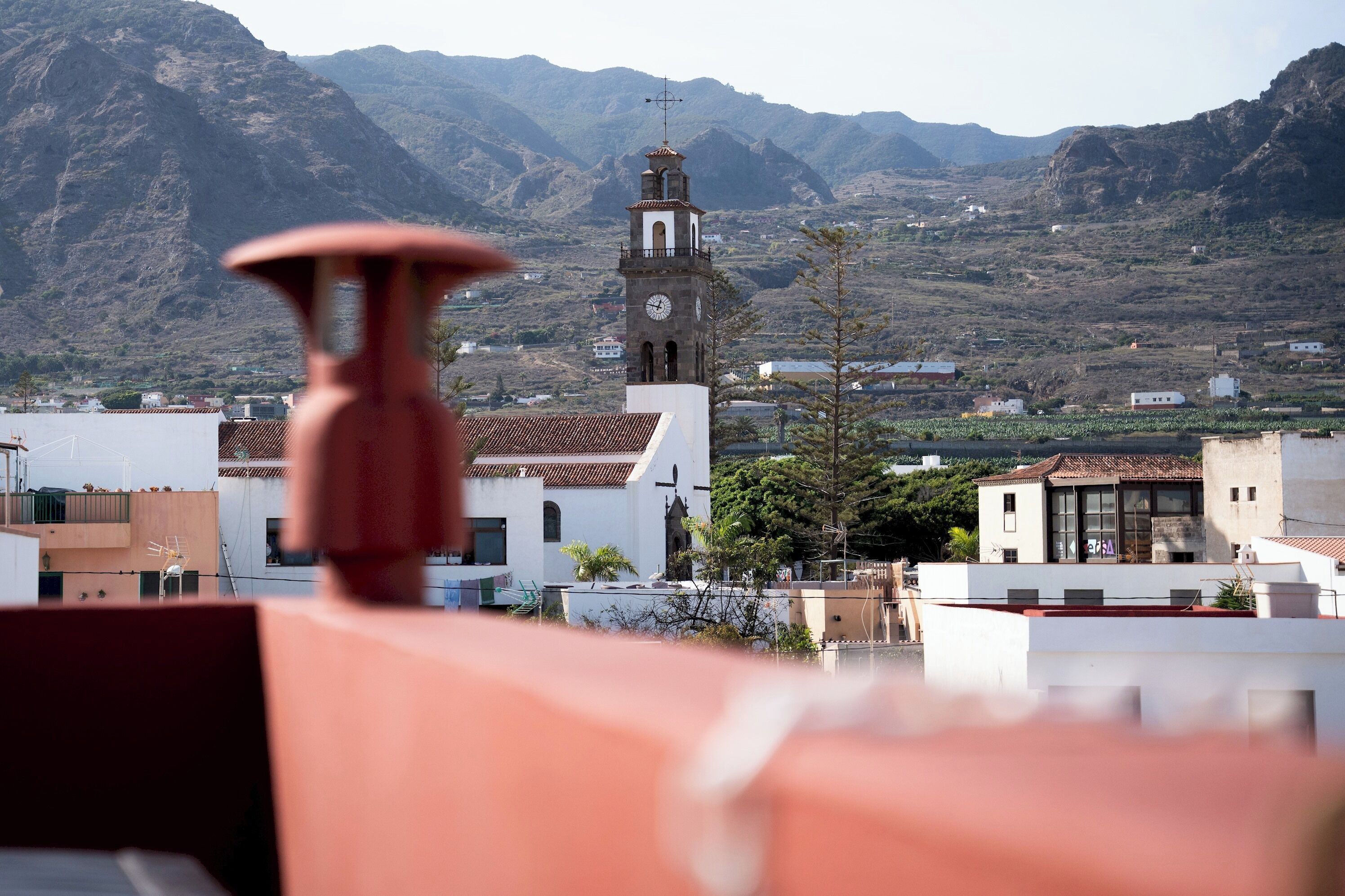 A town with a prominent clock tower, surrounded by mountains.