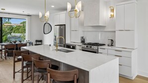 Una cocina moderna con una isla grande, electrodomésticos de acero inoxidable y un comedor con sillas de madera.