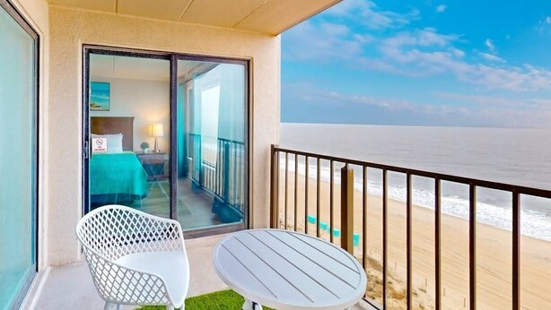 A balcony with a view of the beach, a table, and a chair. - Oceanfront Condo w/ Balcony & Amazing Beach Views (Ocean City)