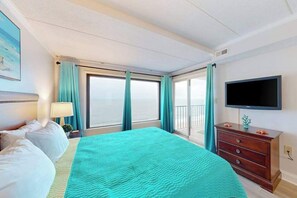 A hotel room with a bed, a TV, a dresser, and a balcony with curtains. - Oceanfront Condo w/ Balcony & Amazing Beach Views (Ocean City)
