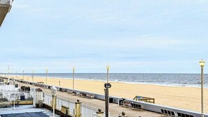 A beachside promenade with a wooden deck, benches, and street lamps. - Decatur House 207 (Ocean City)