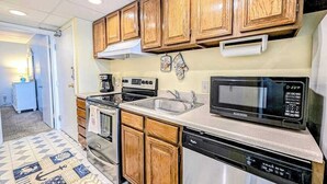 A kitchen with wooden cabinets, a microwave, a dishwasher, and a stove. - Decatur House 207 (Ocean City)