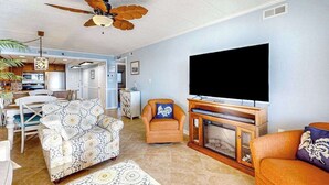 Een woonkamer met een televisie, banken, een plafondventilator en een open haard.