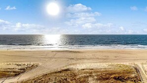 Een strand met een heldere lucht, oceaan en zand.