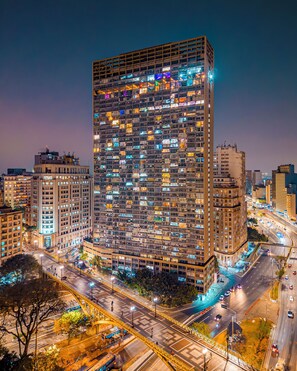 A high-rise building with multiple floors, surrounded by a cityscape at night.