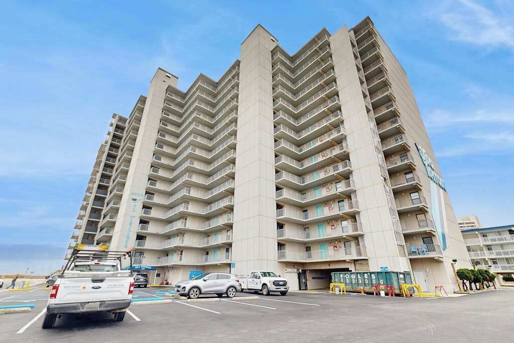 A multi-story hotel with balconies, a parking lot, and a storefront.