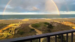 Ein Strand mit Regenbogen, einem Weg und einem Zaun.