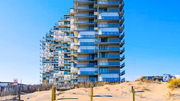 Ein Hochhaus mit mehreren Balkonen in der Nähe eines Sandbereichs.