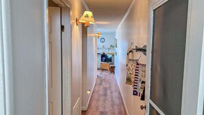 Un pasillo con suelo de madera, una puerta a la izquierda y un mosquitero a la derecha.