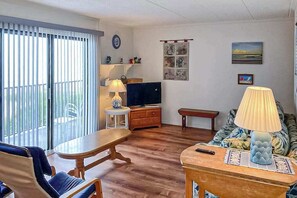 A living room with a TV, a sofa, a table, and a chair. - Bimini # 207 (Ocean City)