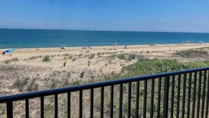 Una playa con gente, cielo despejado y vistas al océano.