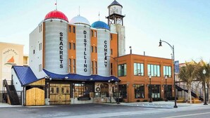 A building with large cylindrical structures labeled 'SECRETS' and 'DISTILLING COMPANY' on the side. - Bahia Vista II 304 (Ocean City)
