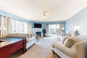 A living room with a fireplace, two sofas, a coffee table, and a TV. - Bahia Vista II 304 (Ocean City)