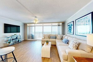 A modern living room with a sofa, coffee table, and TV. - Fountainhead Towers 1310 (Ocean City)