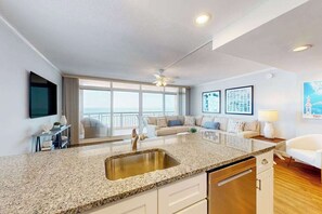 Una cocina moderna con encimera de granito, pileta de acero inoxidable y muebles de cocina blancos.