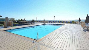 A swimming pool with a wooden deck, lounge chairs, and a clear view of the sea. - Fountainhead Towers 1310 (Ocean City)