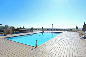 A swimming pool with a wooden deck, lounge chairs, and a clear view of the sea. - Fountainhead Towers 1310 (Ocean City)
