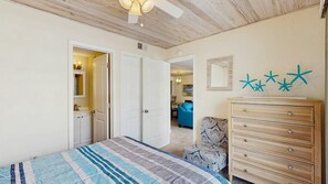 Un dormitorio con cama, cómoda, silla y ventilador de techo.
