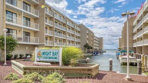 Complejo de condominios frente al agua con varios balcones, un puerto deportivo y un letrero que indica el nombre.