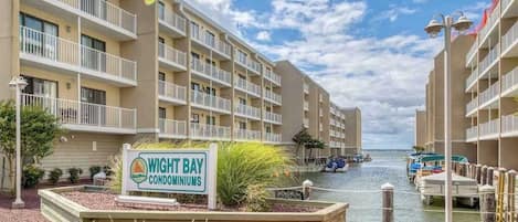 A waterfront condominium complex with multiple balconies, a marina, and a sign indicating the name.