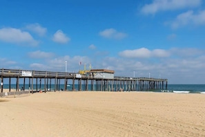 A pier extending into the ocean with a building at the end, a sandy beach, and a clear sky. - Wight Bay South 360 (Ocean City)