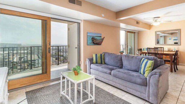 Ein Wohnzimmer mit einer Couch, einem kleinen Tisch, einem Gemälde und einem Balkon mit Blick.
