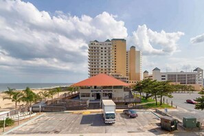 Un hotel con un edificio de techo rojo, aparcamiento y vistas a la playa.
