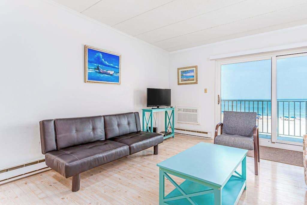 Un salon avec un canapé en cuir, une table basse de couleur turquoise, un téléviseur posé sur un meuble et un fauteuil.