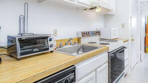 A kitchen with white cabinets, a toaster, a sink, a microwave, and an oven. - Barefoot Country 303 (Ocean City)