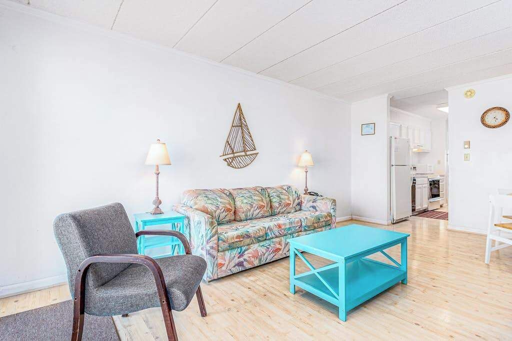 Una sala de estar con sofá, dos sillones, una mesa de centro y una lámpara colgante.