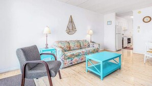A living room with a sofa, two chairs, a coffee table, and a hanging light fixture. - Barefoot Country 303 (Ocean City)