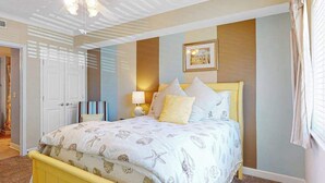 Un dormitorio con cama, mesita de noche, lámpara y un cuadro en la pared.