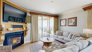 A living room with a fireplace, a sofa, a coffee table, and a balcony with a view. - Oceanfront Belmont Towers Condo w/ Private W/D, Shared Pool, AC, Free WiFi (Ocean City)