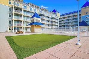 A multi-story hotel with balconies, a central courtyard with artificial grass, and a picnic table. - Belmont Towers 801 (Ocean City)