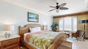 A hotel room with a bed, a ceiling fan, a window with curtains, a chair, and a lamp. - Belmont Towers 801 (Ocean City)