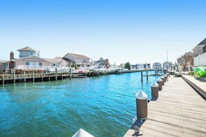 A waterfront property with a dock, houses, and a clear blue sky. - Canalfront House w/ Private Deck, Central AC, Free WiFi, Bay Views, Washer/Dryer (Ocean City)