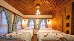 A room with two beds, wooden walls, a wooden ceiling, and a chandelier.