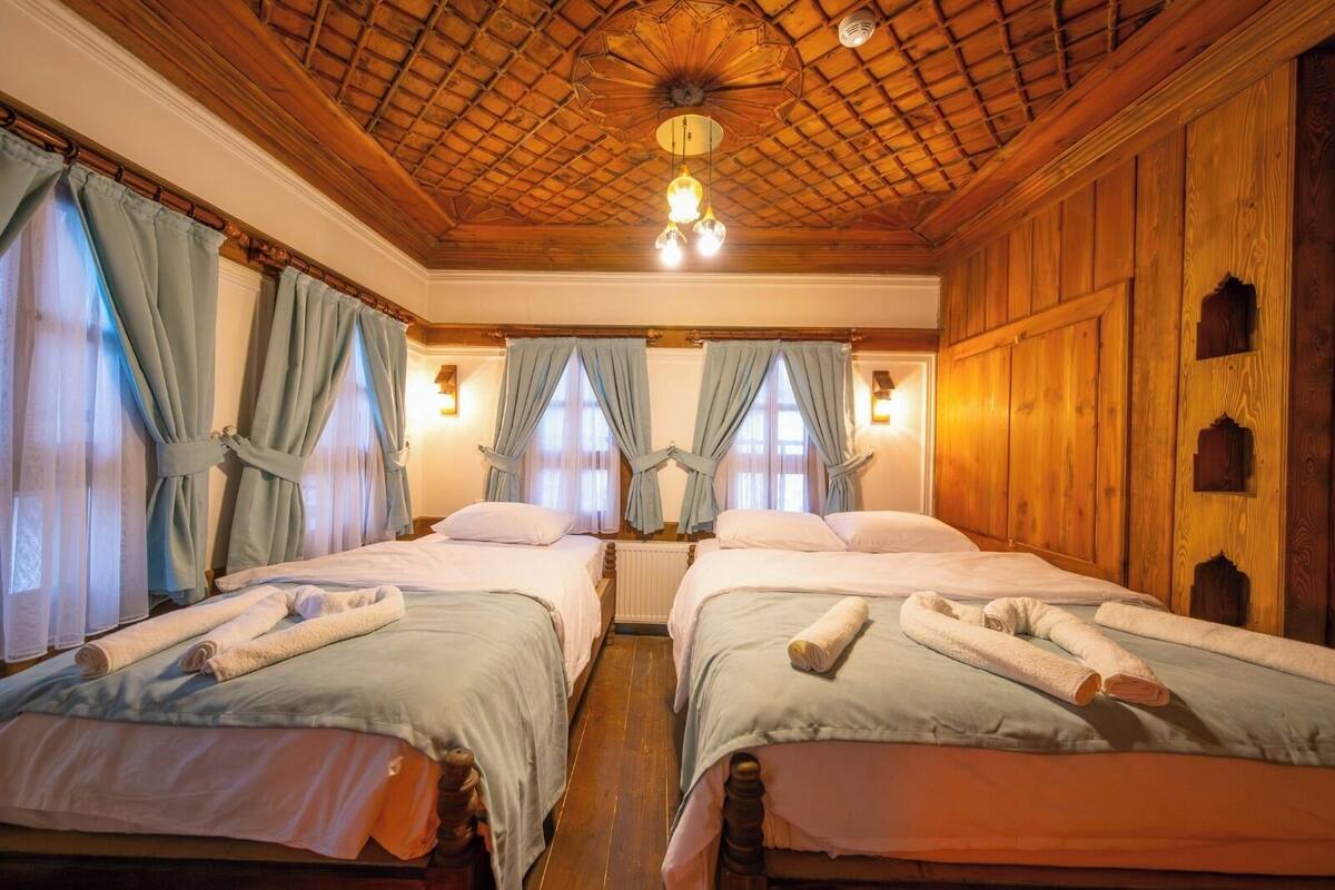 Quarto com duas camas, paredes e teto de madeira, e um candelabro.
