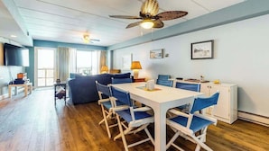 Ein modernes Wohnzimmer mit Essbereich, Deckenventilator und Fernseher.