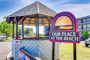 Ein Kiosk am Strand mit einem Schild, auf dem 'OUR PLACE AT THE BEACH' steht.