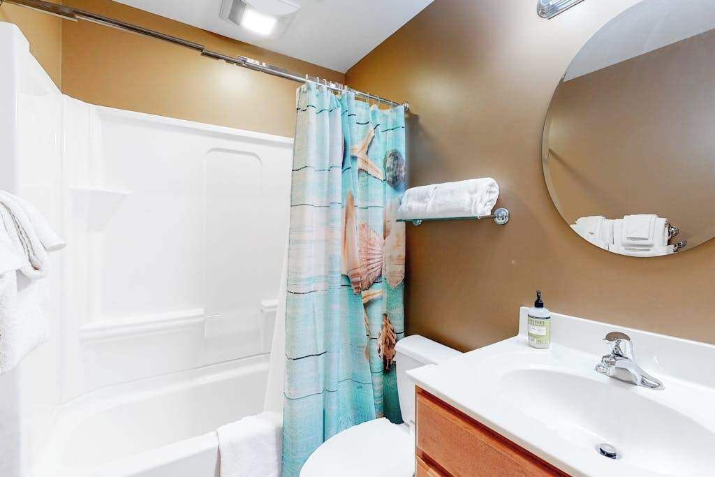 Un baño con bañera, inodoro, lavamanos y espejo.