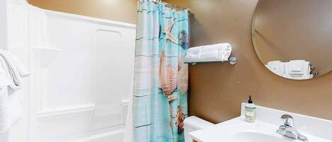 Un baño con bañera, inodoro, lavamanos y espejo.